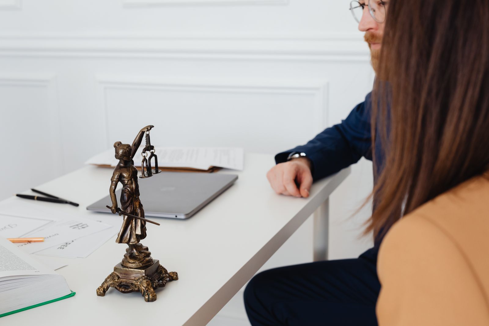Attorneys discussing documents beside a Lady Justice statue